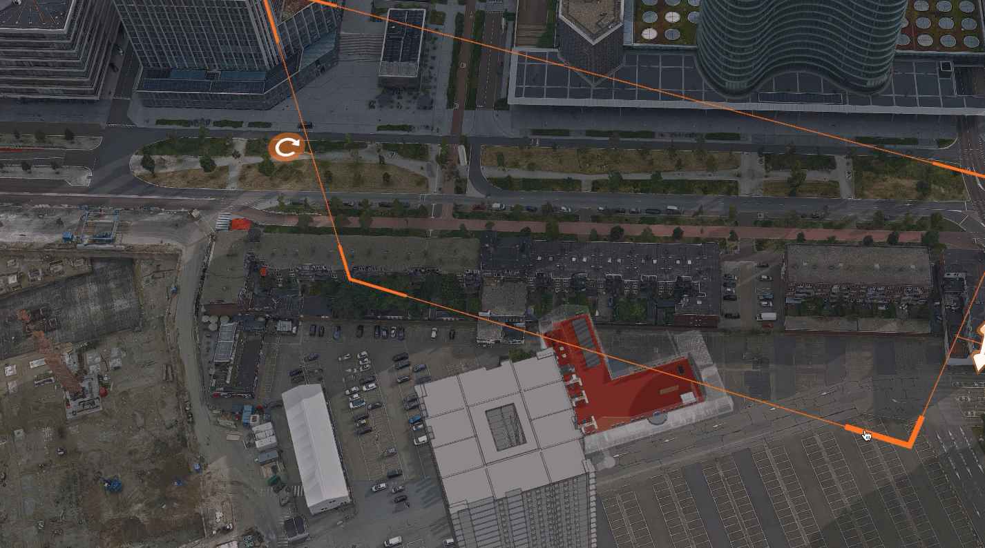 Aeriel view of a tall, gray building model and a parking lot with cars below