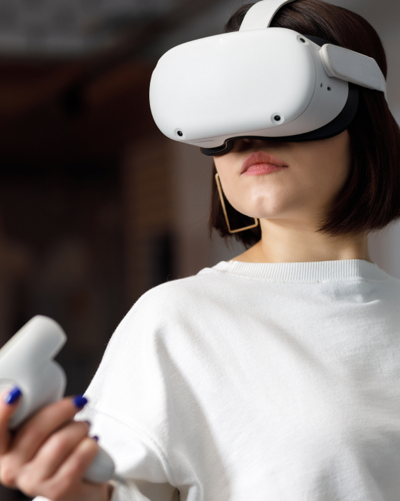 Women with short brown hair wearing a white t-shirt and large white XR goggles over her eyes