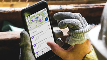 Closeup of a hand using a mobile phone to collect asset data in the field