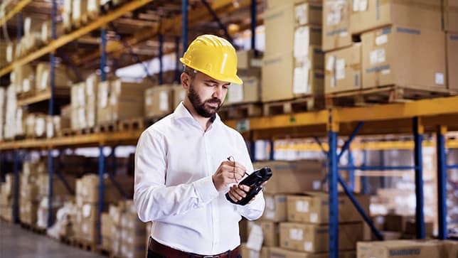 Man wearing a yellow hard hat in a warehouse using a tablet ,Man wearing a yellow hard hat in a warehouse using a tablet 
