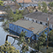 Damaged homes in a flooded neighborhood with a fallen tree resting on power lines