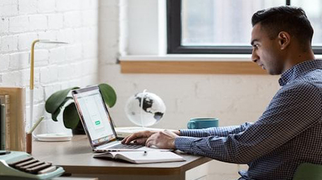 Man sitting at a desk typing on his laptop and launching an ArcGIS Hub template