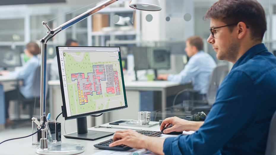 Man sitting at a desk and looking at an indoor map with data points on a desktop monitor,Man sitting at a desk and looking at an indoor map with data points on a desktop monitor