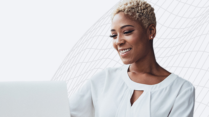 A person in a stylish white blouse using a laptop and smiling