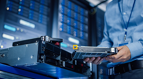 A person examining a hard drive in a computer server room