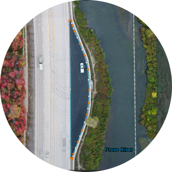 An aerial drone view of a highway near fall foliage and green trees