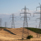 Rolling brown field with black power towers and connecting power lines