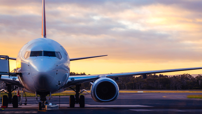 Front of a commercial airplane on a runway at dusk
