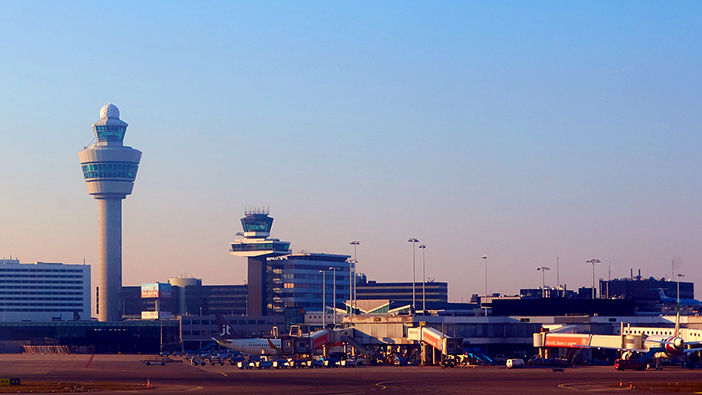 Airport runway with large control tower and several vehicles on the runway 