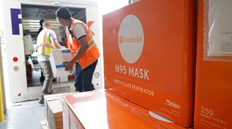 Workers moving N95 mask boxes to and from a FedEx van