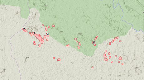 A map with land shaded in green and beige with several red polygons dispersed throughout