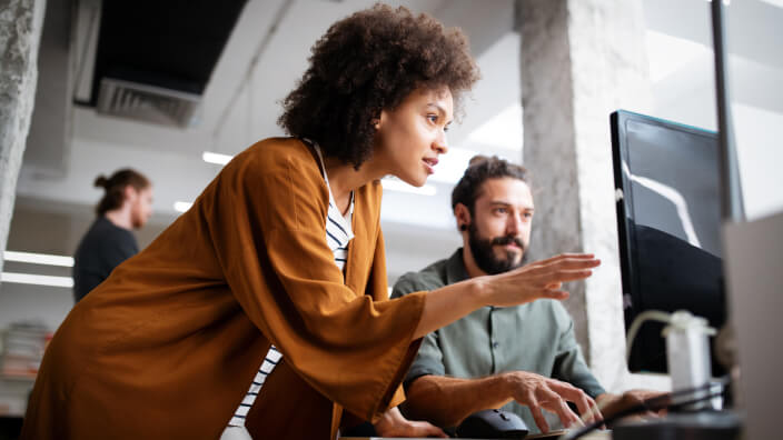 man looking at PC and woman pointing at PC in an office setting