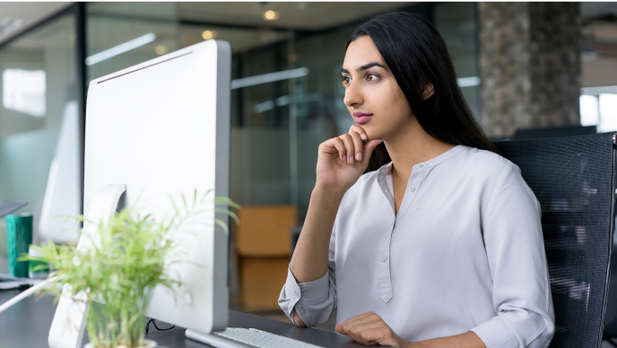 A woman in her office reading a story on her desktop monitor