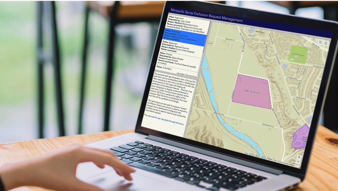 A person working on a laptop displaying a map and text representing a digital dashboard 