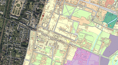 A colorful city map with some areas shaded pale green, pink, and purple, and other areas realistically 3D-modeled