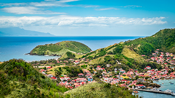 A coastal area with buildings dotting green, rolling hills