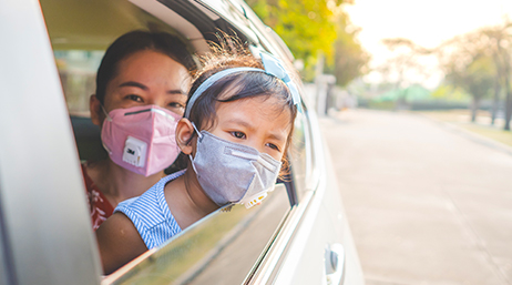An adult holding a child while they looking out of a rolled down car window
