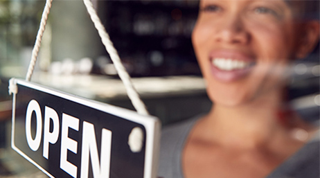 Person looking through a glass window with an open sign