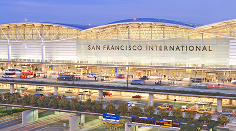 An exterior image of San Francisco International Airport with many cars whizzing past under a twilight sky