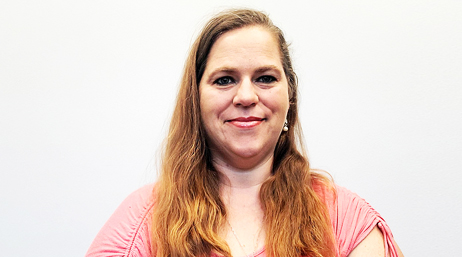 Amanda Parisi with long auburn hair, wearing a pink shirt