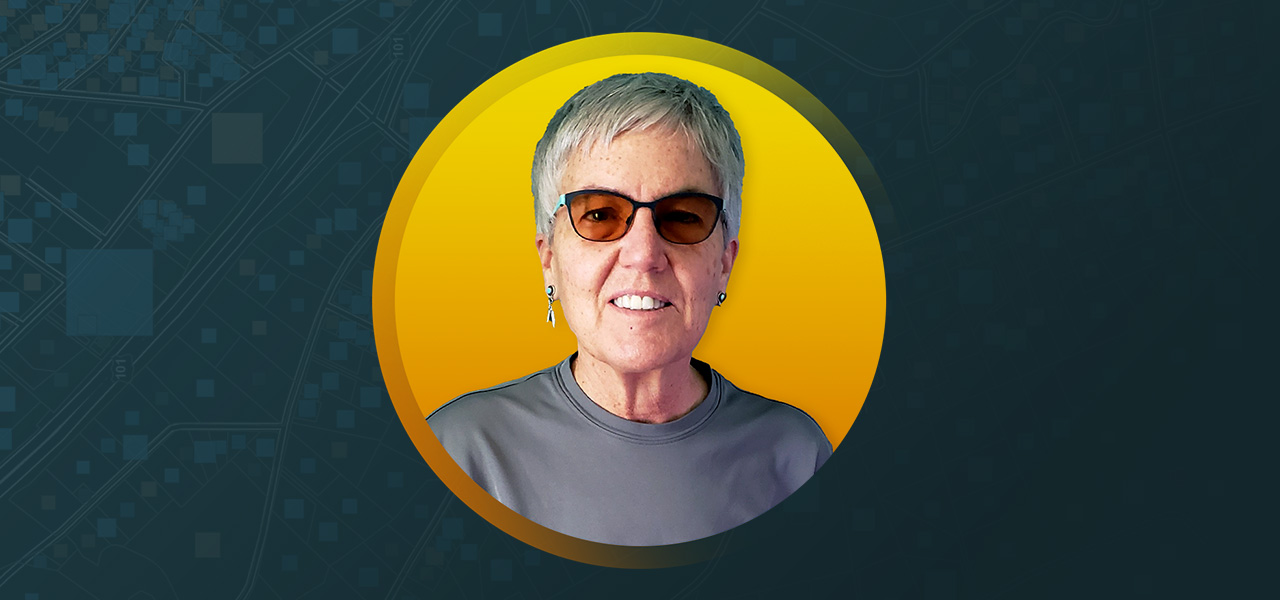 Portrait photo of Nancy Lewis smiling in dark glasses and a gray shirt