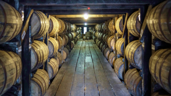 A bourbon rickhouse with rows of large wooden barrels stored in racks to the ceiling
