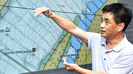 A person referring to a large nautical map in the background