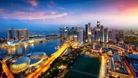 An aerial view of Singapore’s downtown core with high rise buildings, Marina Bay, and the Singapore Strait in the distance