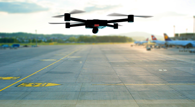 A closeup photo of a drone flying over a runway near sunset on a hazy day