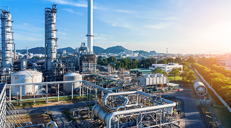 A industrial facility in bright silver surrounded by a tree-filled modern city with a blue sunrise sky overhead