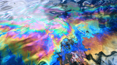 A closeup of the shining rainbow surface of oil-coated water
