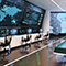 A corporate security room with large televisions displayed around the room with emergency maps and dashboards and a sand table in the middle of the room