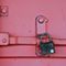 A close-up photo of a rusty black padlock on a painted pink metal door