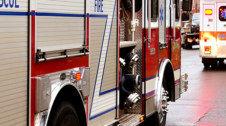 A photo of a red fire truck following an ambulance down a city street