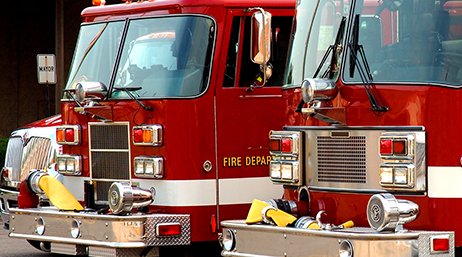 A closeup photo of three red fire engines parked in a row