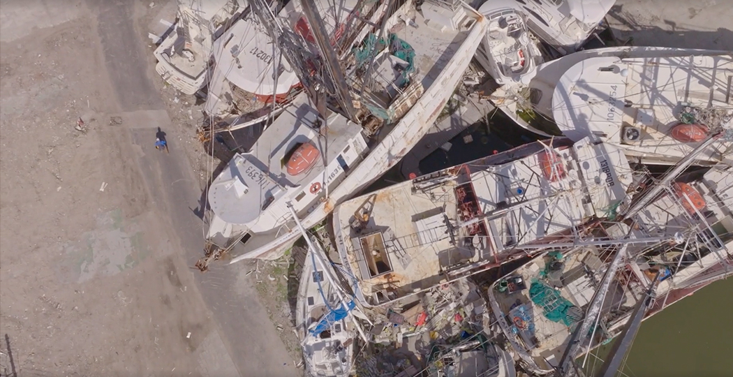 An aerial view of damaged boats piled together after a storm