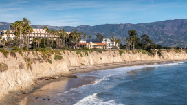 An upscale community lining a towering cliffside beside a calm beach