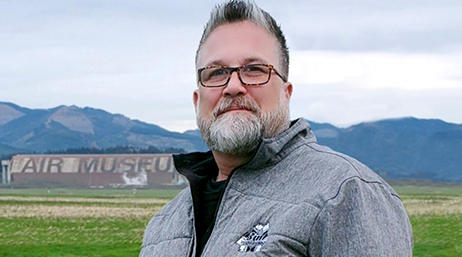 Portrait of Chris Polley smiling in a gray windbreaker