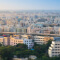An aerial photo of a large city in India with many beige highrise buildings beneath a clear blue sky
