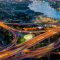 An aerial photo of a busy city surrounded by a network of highways brightly lit up for night under a blue sunset sky
