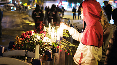 A person standing in lighting a candle at a makeshift memorial for people lost in an earthquake