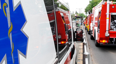The side of a parked ambulance and the back of parked fire trucks