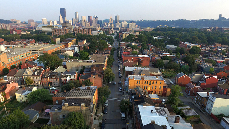 A densely built neighborhood with a city skyline in the distance