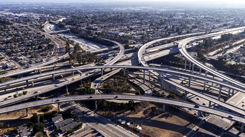 An aerial view of a complex freeway interchange dotted with cars
