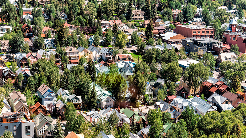 Many suburban houses clustered closely together amidst green trees