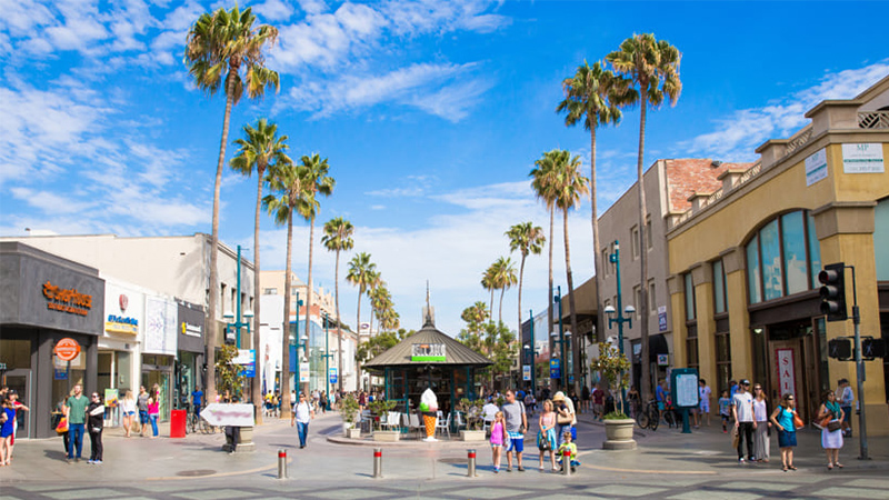 A rendering of a commercial promenade lined with palm trees and populated with people