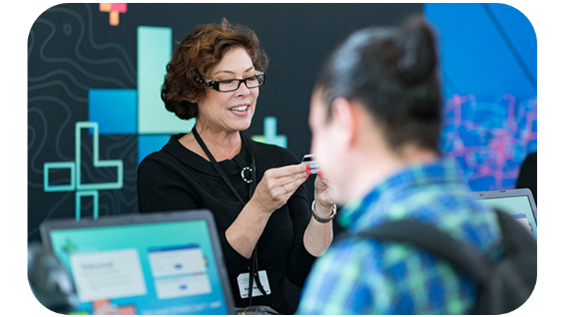 A person wearing glasses and looking at a credit card while working at a conference service desk