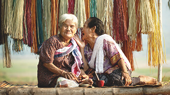 Two women sitting outside and one is talking with the other