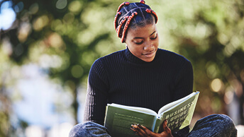 A woman sitting outside and reading a book