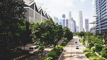 A city skyline with tall skyscrapers and green parkways
